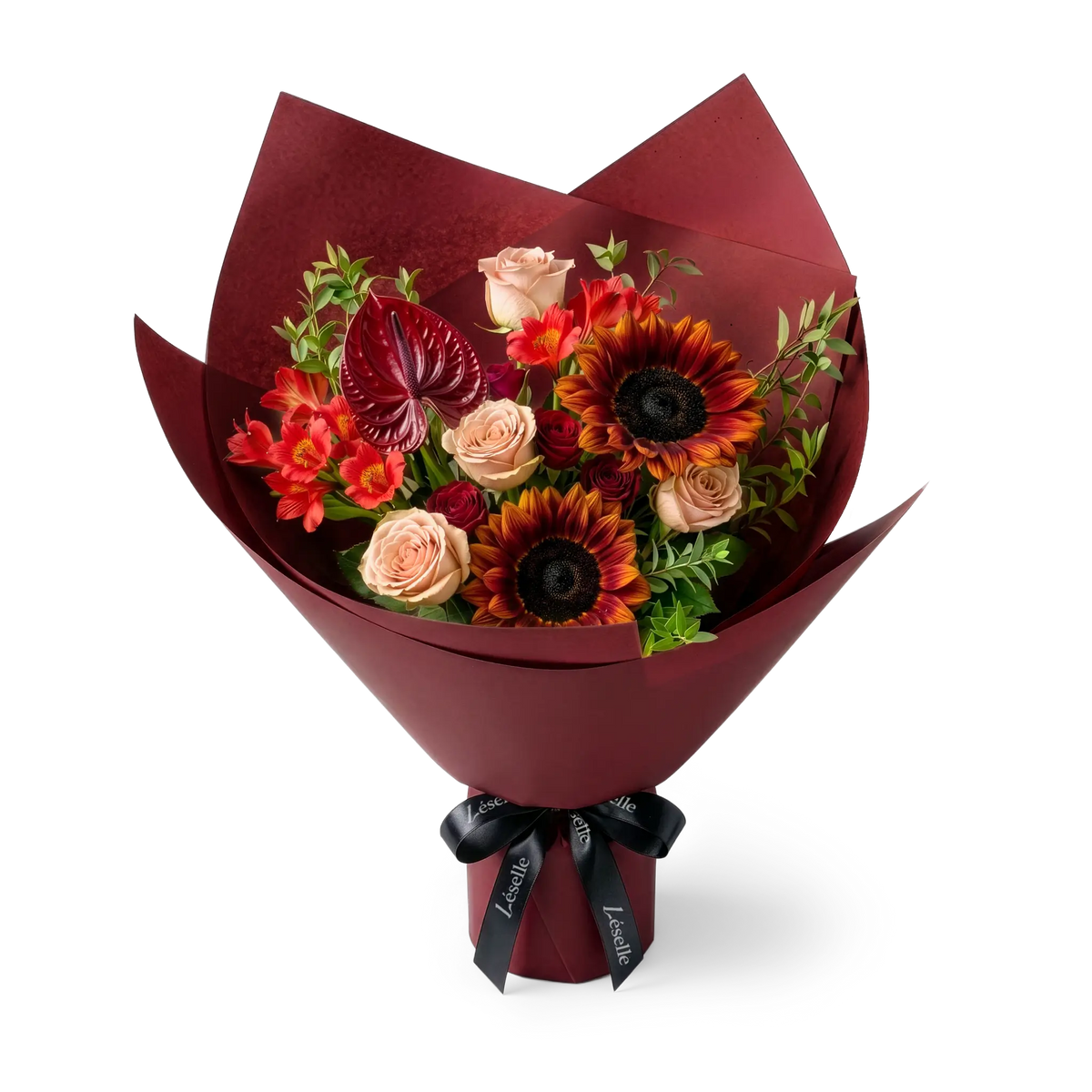 A wrapped flower bouquet featuring burgundy sunflowers, cappuccino roses, a dark red anthurium, and green foliage, wrapped in a burgundy paper sleeve with a black ribbon, on a transparent background.